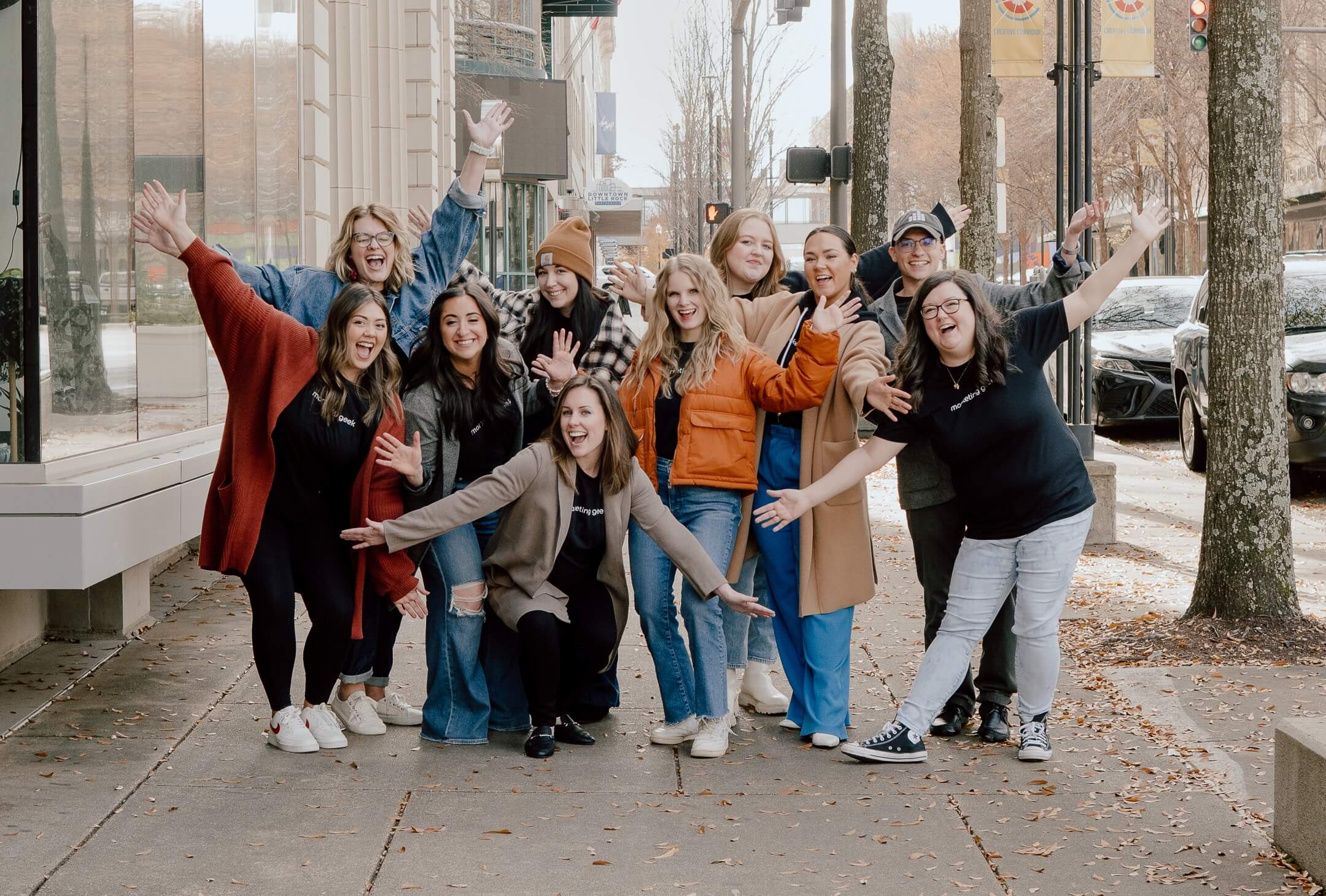Cheerful Marketing Geeks pose with hands extended