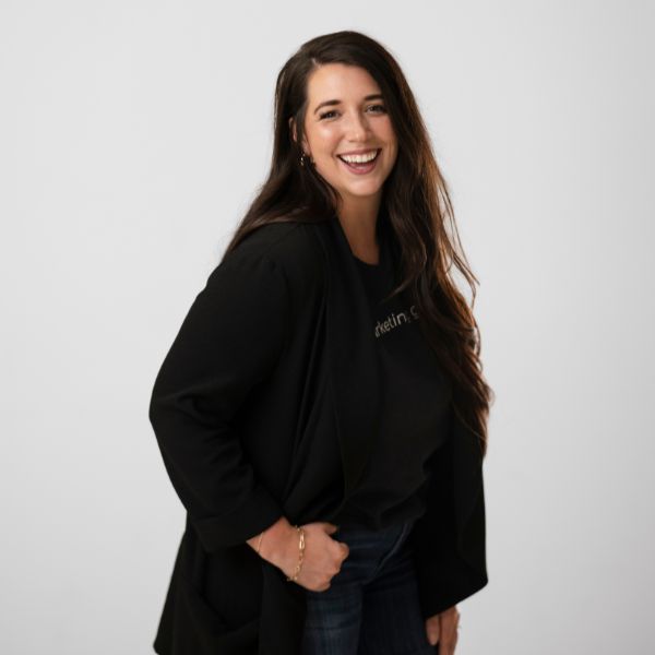 Nikki, the director of operations, smiles confidently in a black blazer and marketing geek shirt.