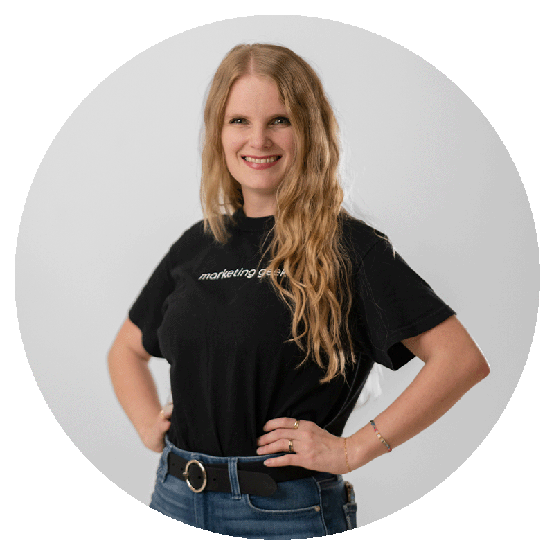 Kait Circle Kait Hill, founder and chief geek, stand with her hands of her hips confidently with a radiant smile, exuding joy and ambition.