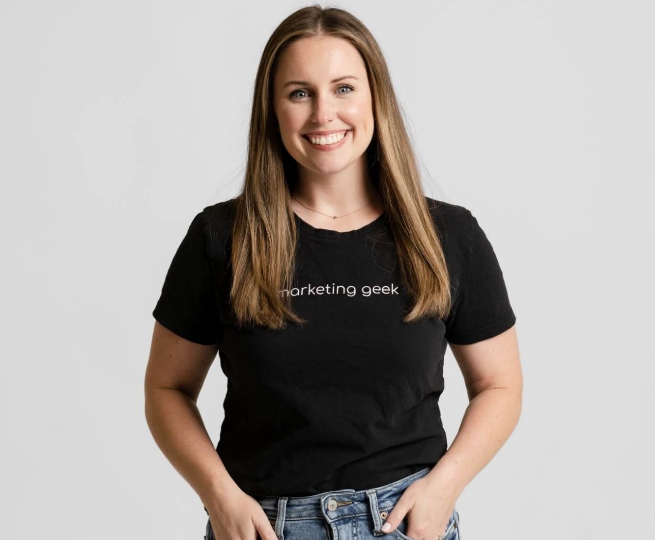 Kenzie Cundall Happiness Geek, stands proudly smiling in a black marketing geek t-shirt.