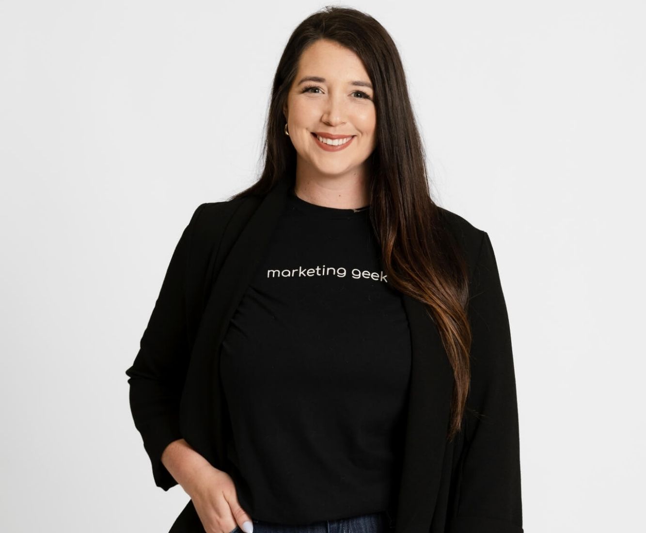 Kenzie Cundall Happiness Geek, stands proudly smiling in a black marketing geek t-shirt.