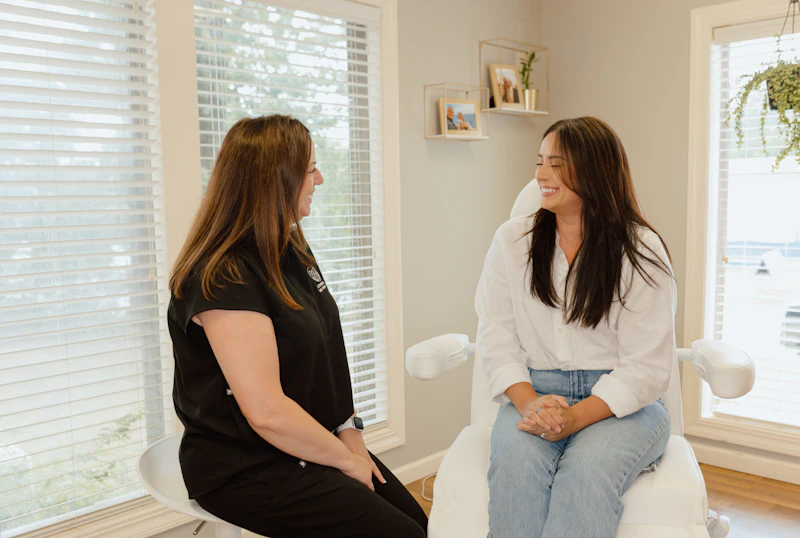 A woman seated on a couch, engaging with two individuals who are sitting in front of her in a casual setting.